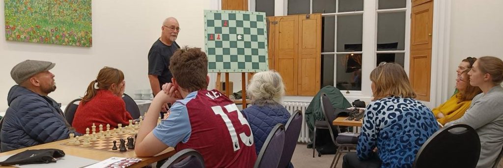 Chess players looking at an instructor.